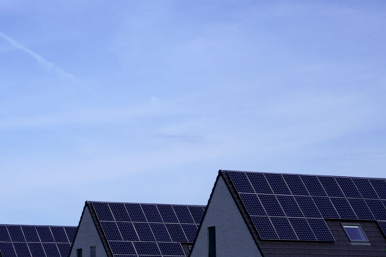 Services Modern Belgian houses with solar panels on rooftops under a clear blue sky.